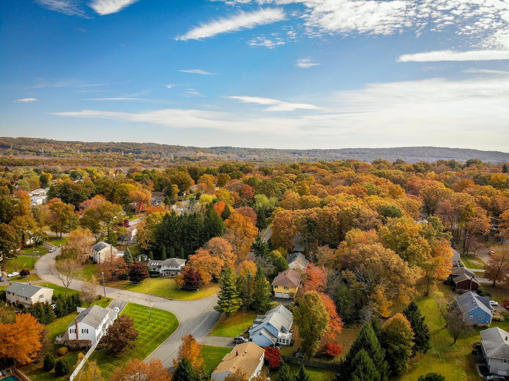 A stunning aerial view of a vibrant countryside with autumn foliage and clear blue skies.